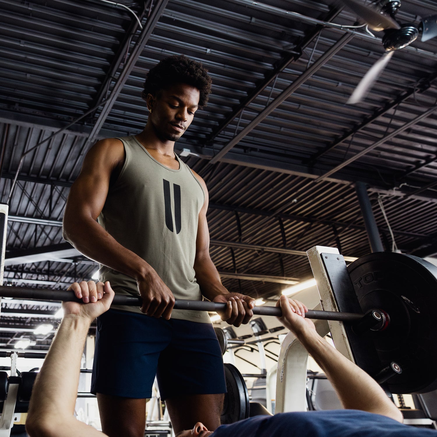 Man wearing U Tank holding barbell.